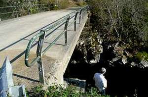 La piedra está situada junto a un puente de moderna construcción, en la orilla de Agolada. 